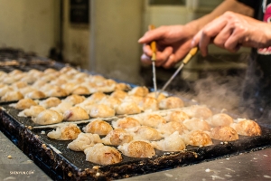 Takoyaki&mdash;Osaka's signature street food&mdash;octopus dumplings that are shaped and turned with steel pins while cooking.
